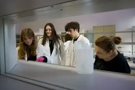 Uczniowie w fartuchach podczas zajęć laboratoryjnych